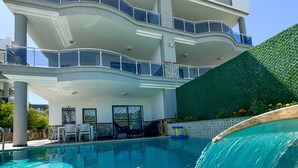 A multi-story building with a swimming pool and a waterfall feature. - Villa Begonvil (Kusadasi)