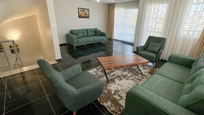 Una sala de estar con un sofá verde, una mesa de centro de madera y una alfombra estampada.