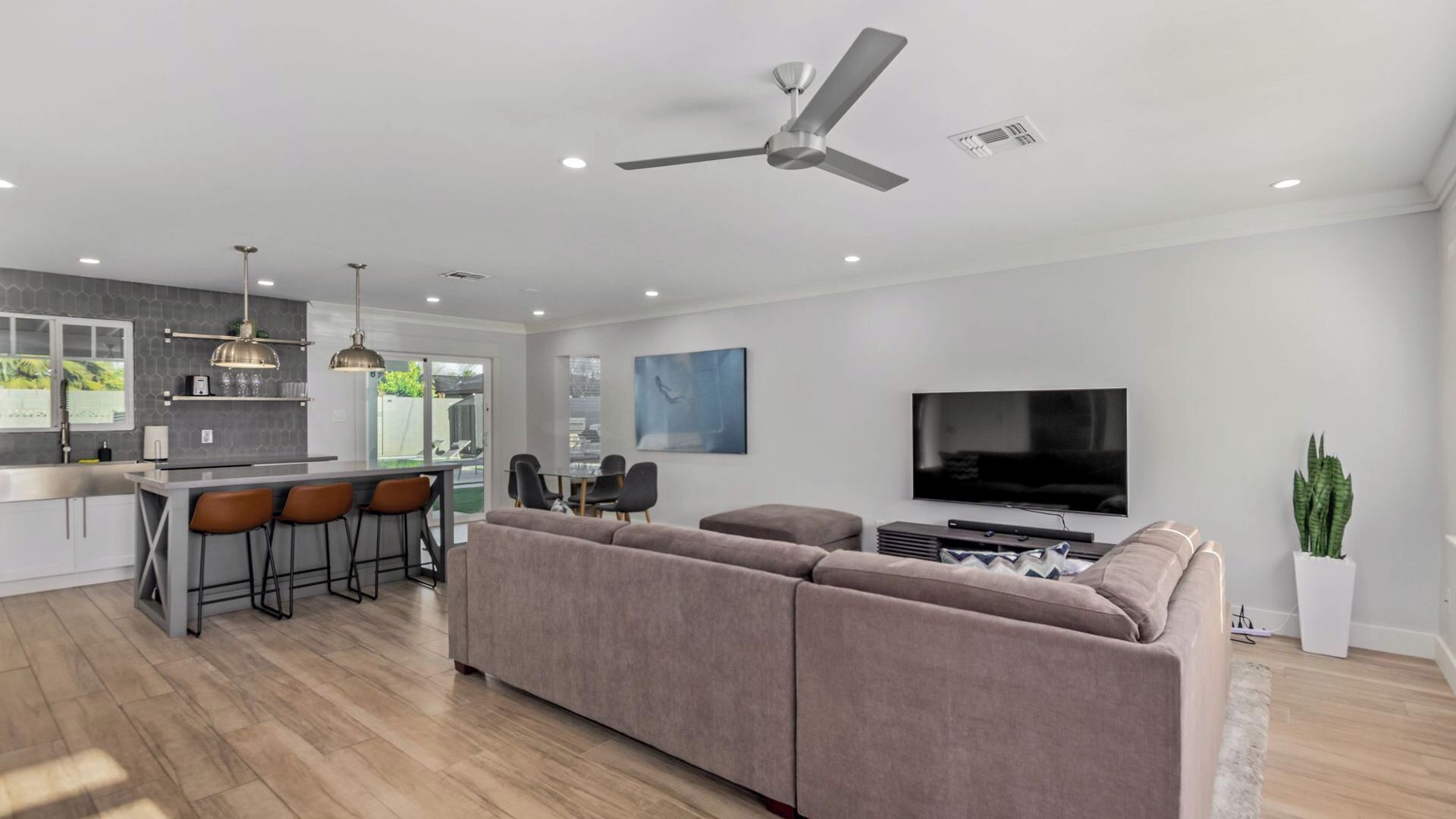 A modern living space with a kitchen, dining area, and a large TV.