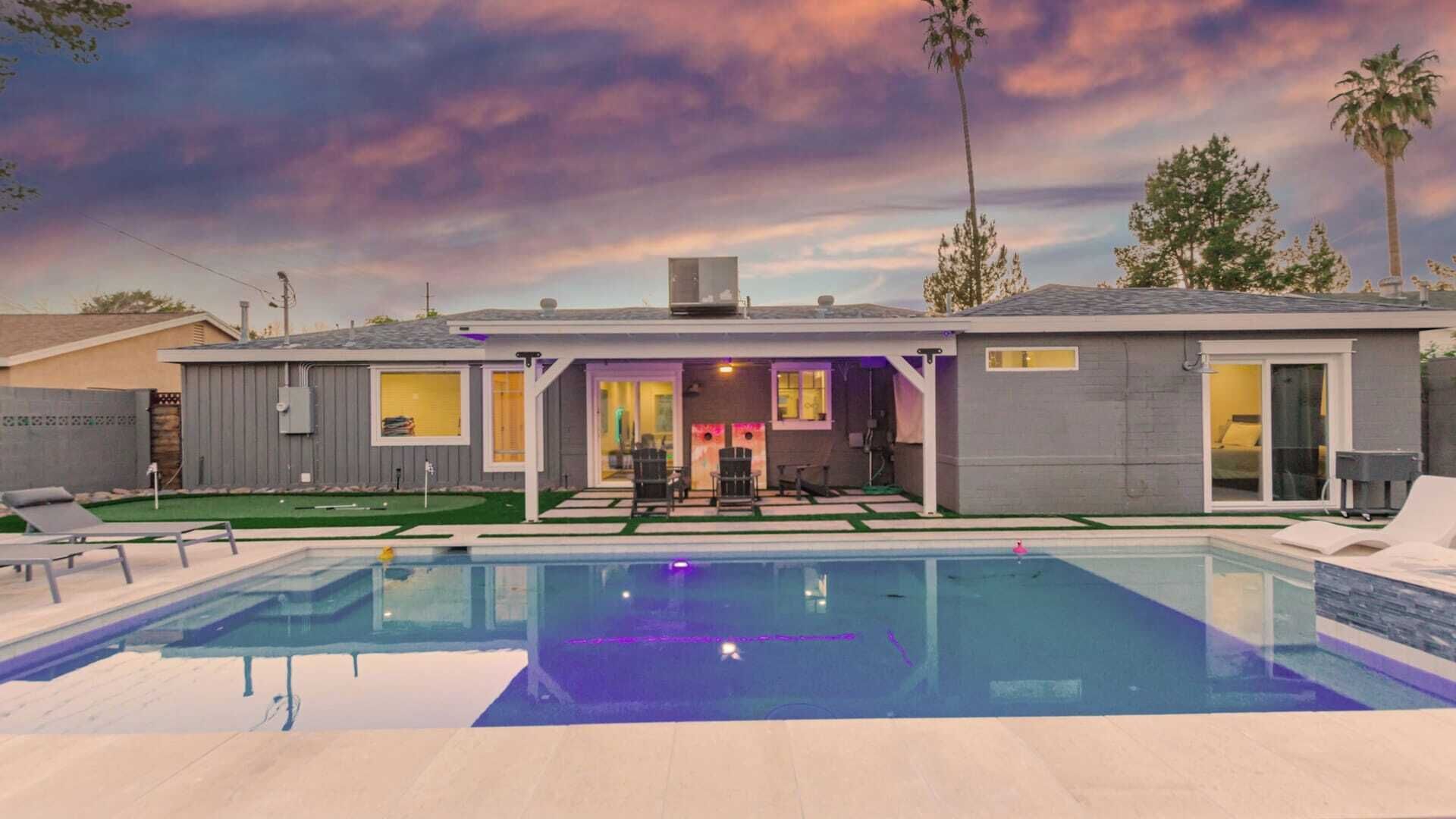 Una casa moderna con piscina, un porche cubierto y un césped bien cuidado.