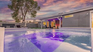 Una piscina con sillas de descanso y una zona cubierta con vistas al cielo.