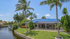 A waterfront property with a pool, palm trees, and a boat dock. - For your family, perfect location and amenities that leave nothing to be desired (Cape Coral)