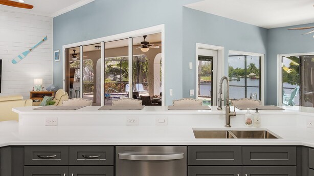 A modern kitchen with a large island, white countertops, and a stainless steel sink. - For your family, perfect location and amenities that leave nothing to be desired (Cape Coral)