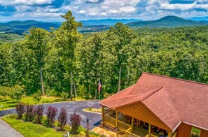 A lodge with a red roof, surrounded by dense forest and mountains.
