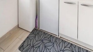 Una cucina moderna con mobili bianchi, una schiena di piano di lavoro in marmo nero e una lampada a sospensione nera.