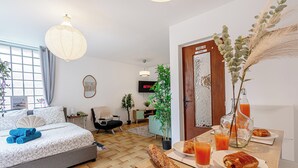 Una camera d'albergo moderna con un letto, un tavolo per la colazione, prodotti per la colazione e una TV.