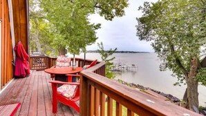 A wooden deck with a table and chairs, overlooking a calm body of water. - Lakefront Lake Poinsett Cottage with Private Beach (Castlewood)