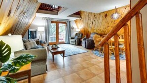 A cozy living room with a sofa, coffee table, and chairs, wooden walls, and a staircase. - Lakefront Lake Poinsett Cottage with Private Beach (Castlewood)