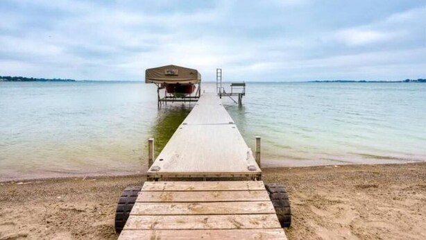 A wooden pier leading to a covered boat dock on a calm body of water. - Lakefront Lake Poinsett Cottage with Private Beach (Castlewood)