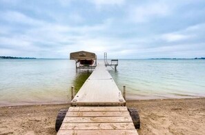 A wooden pier leading to a covered boat dock on a calm body of water. - Lakefront Lake Poinsett Cottage with Private Beach (Castlewood)