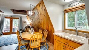 A kitchen with wooden cabinets, a sink, and a dining area with a table and chairs. - Lakefront Lake Poinsett Cottage with Private Beach (Castlewood)