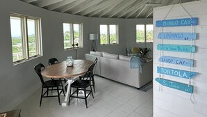 A spacious room with a dining area, a sofa, and a wall with name signs. - The Round House (St Thomas)