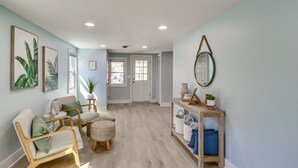 A spacious hallway with a light blue wall, wooden flooring, and a seating area with a chair and ottoman. - Bayfront Maryland Retreat w/ Deck, Near Beaches! (North Beach)