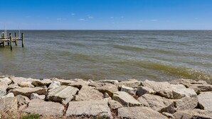 A rocky shoreline with a wooden pier extending into calm waters. - Bayfront Maryland Retreat w/ Deck, Near Beaches! (North Beach)