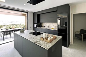 A modern kitchen with a large island, dark cabinetry, and a view of the outdoors. - Salobre Los Veroles Golf, Maspalomas (Maspalomas)