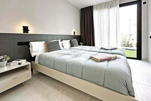 A modern bedroom with a bed, bedside tables, and a view of the outdoors. - Salobre Los Veroles Golf, Maspalomas (Maspalomas)