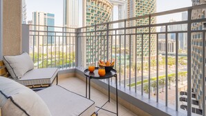 Un balcon doté d’un canapé et d’une table, offrant une vue sur les immeubles modernes.