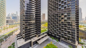 Un immeuble moderne de grande hauteur, doté d’une façade originale, entouré de palmiers et surplombant un ciel dégagé.