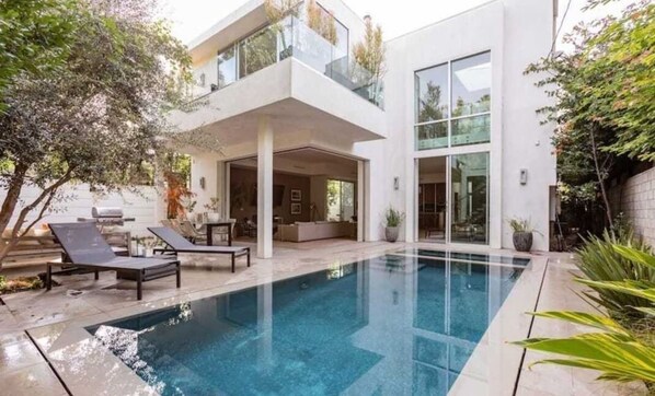 A modern house with a swimming pool, outdoor seating, and a glass-enclosed balcony. - Stunning Home: Pool, Hot Tub, Fire Pit, Dogs OK (Los Angeles)