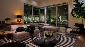 A modern living room with a sofa, coffee table, and a large window providing a view of the outdoors. - Stunning Home: Pool, Hot Tub, Fire Pit, Dogs OK (Los Angeles)