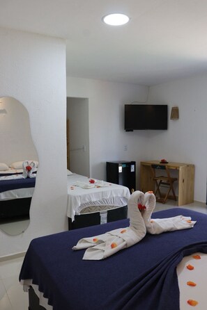 Ein Hotelzimmer mit zwei Betten, einem Flachbildfernseher, einem Schreibtisch und einem Stuhl.