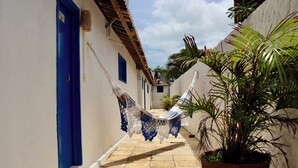 Un callejón estrecho con una hamaca colgada entre dos edificios, una planta en maceta y una puerta azul.