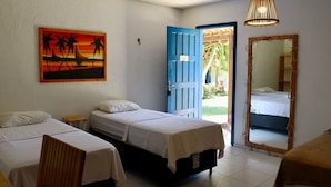 Una habitación con dos camas, un cuadro de una puesta de sol, una puerta azul y un espejo.
