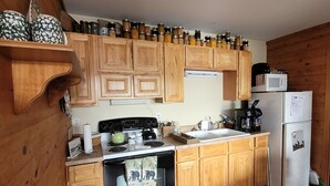 Cucina con mobili in legno, fornello, microonde e frigorifero.