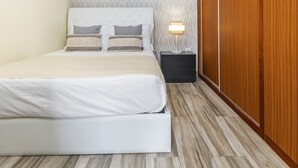 A bedroom with a bed, a nightstand, a lamp, and a wooden wardrobe. - Cantinho do Sol by Homie (Ribeira Brava)