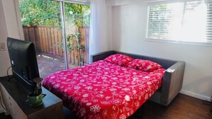 Een slaapkamer met een bed, een televisie en een raam.