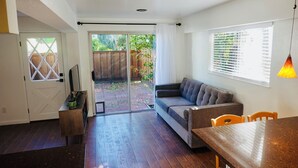 Een moderne woonkamer met een bank, een eettafel en een glazen schuifdeur die leidt naar een terras.