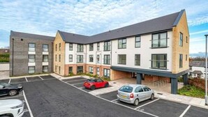 A multi-story building with a parking lot in front. - Gospel Heights by Guestz (Heswall)