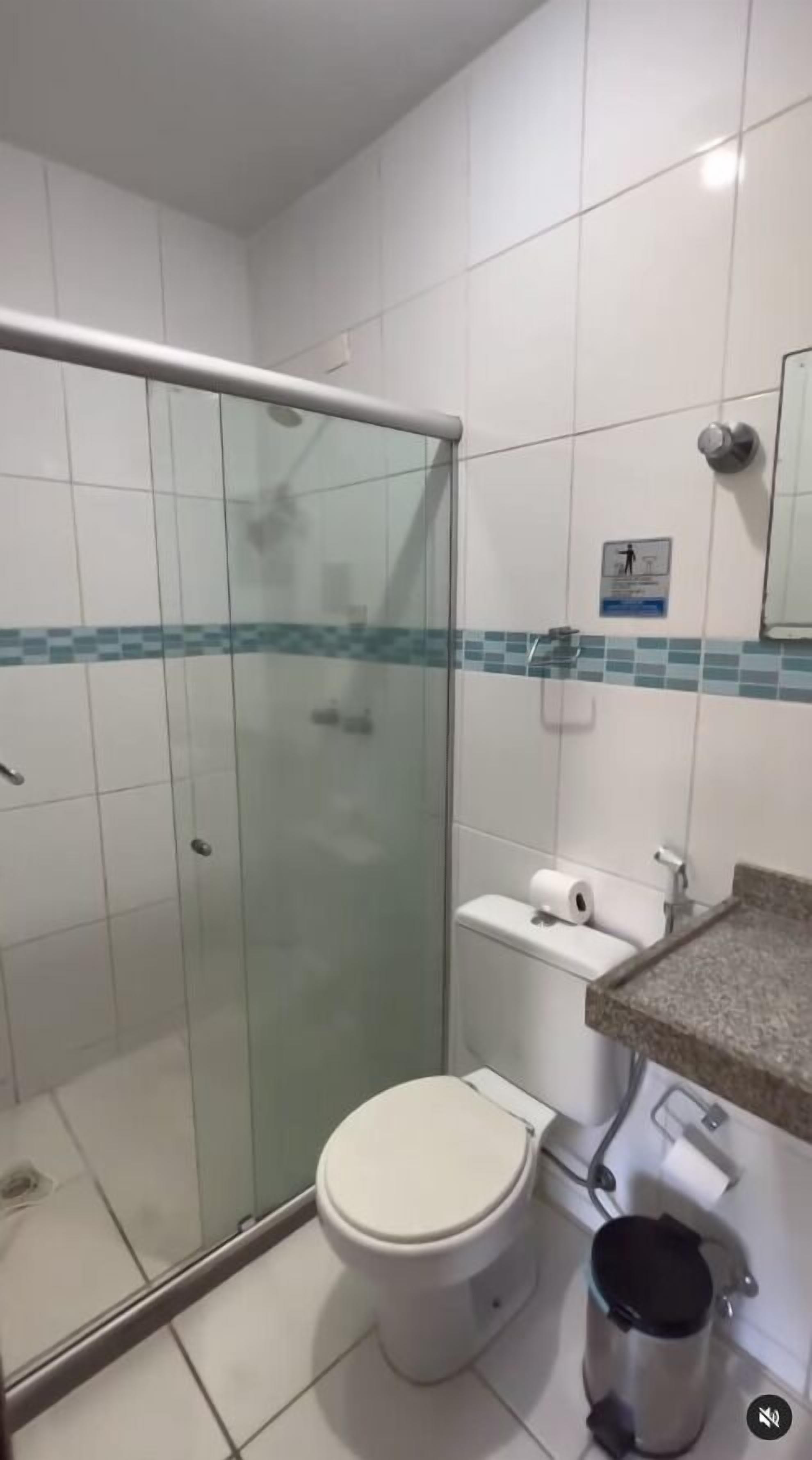 A bathroom with a glass-enclosed shower, a toilet, and a sink with a countertop.