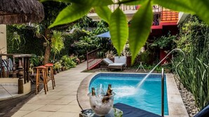 A pool area with a thatched roof, lounge chairs, and a bar area with stools. - Baobá Pousada e SPA (Olinda)