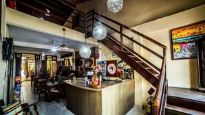 A restaurant with a central counter, wooden staircase, and hanging spherical light fixtures. - Baobá Pousada e SPA (Olinda)
