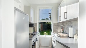 A modern kitchen with stainless steel appliances, a window with a view of the garden, and a built-in oven. - Beautiful Ground Floor Apartment (Perth)