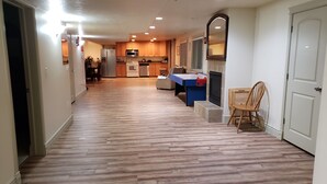 A hallway leading to a kitchen with wooden flooring, a dining area with a table and chairs, and a fireplace. - 3 Bedroom Basement Suite with Kitchen (Centerville)