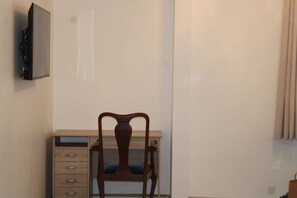 Work from a comfortable desk with a chair, featuring a flat-screen TV and a window with curtains.