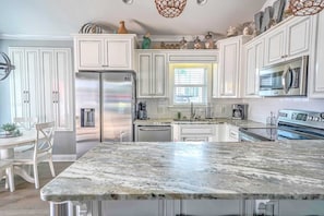 Una cocina moderna con armarios blancos, electrodomésticos de acero inoxidable y encimera de mármol.