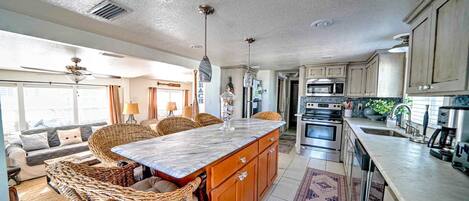 A spacious kitchen with a large island, modern appliances, and a view to the living area.