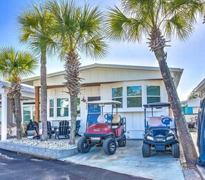 A two-story building with a garage, two golf carts, and palm trees.