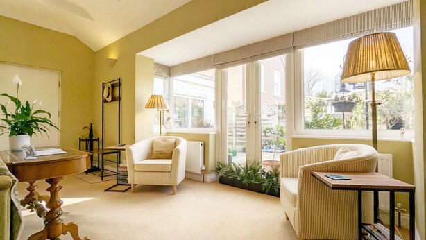 A cozy room with a large window, a chair, a table, and a lamp.
