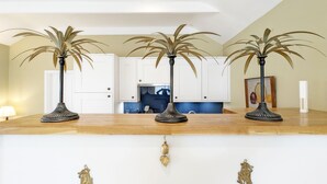 A kitchen with white cabinets, a wooden countertop, and three decorative palm plants.