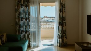 Ein Zimmer mit Blick auf eine Küstenlandschaft, inklusive Balkon mit Ausblick auf Strand und Gebäude.