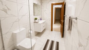 A modern bathroom with a toilet, sink, and shower area.