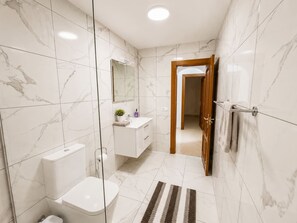 Une salle de bain moderne équipée de toilettes, d’un lavabo et d’une zone douche.