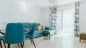 Ein modernes Wohnzimmer mit einem blauen Sofa, einem passenden Sessel und einem kleinen Beistelltisch.