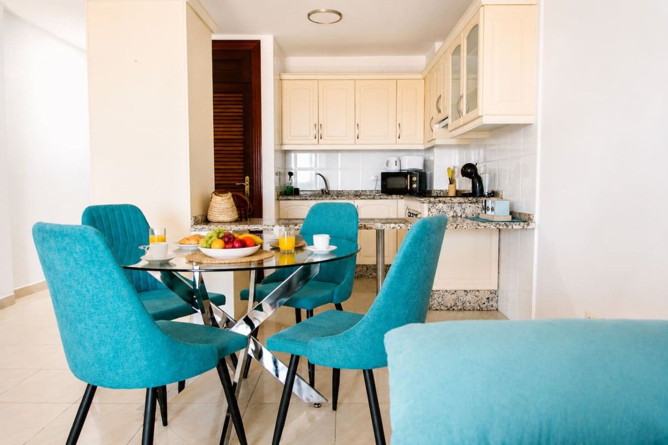Una cocina compacta con gabinetes blancos, un microondas y una cafetera.