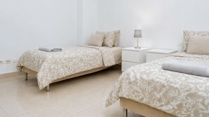 A hotel room with two beds, a nightstand, and a lamp.
