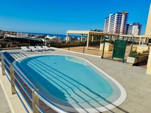 Une piscine sur le toit offrant une vue dégagée sur la mer et les bâtiments en arrière-plan.